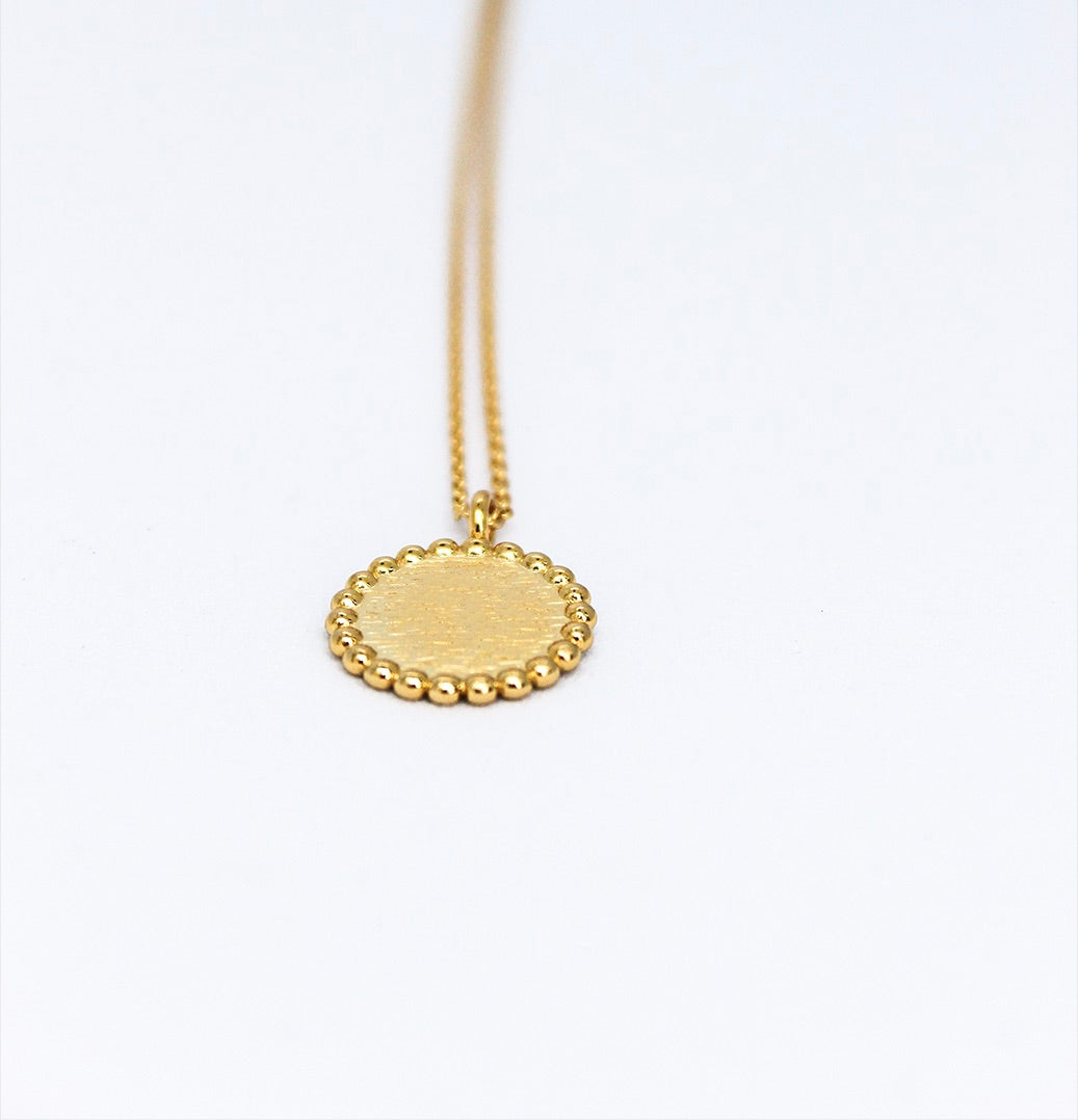Bovenaanzicht van graveerbare goldplated zilveren herinneringsketting met reliëf en bolletjes op de zijkant.