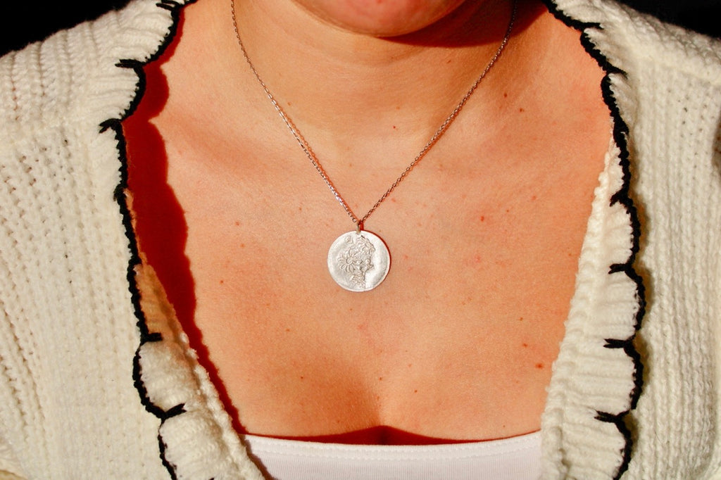 Néhlia's herinneringssieraden:  Handgemaakte zilveren madeliefje hanger gedragen aan een fijne ketting als betekenisvol geboortesieraad.