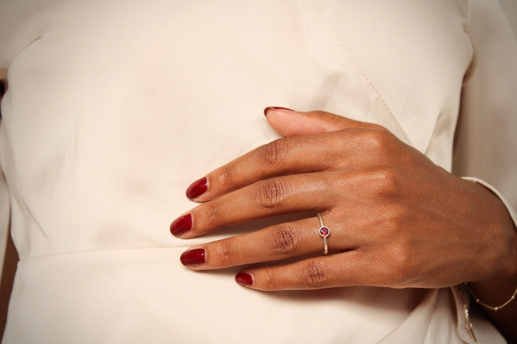 De zilveren Aura ring met dieprode granaat gedragen als betekenisvol en elegant geboortesieraad.