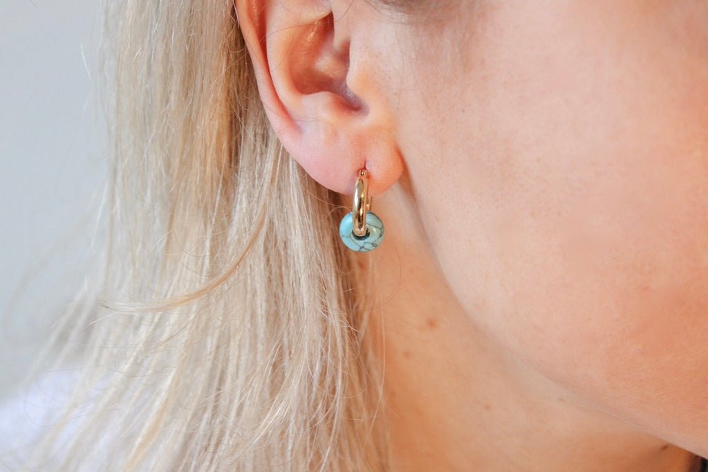 Gold-plated zilveren Lyra oorbellen met turquoise van Néhlia gedragen in vrouwen oor.